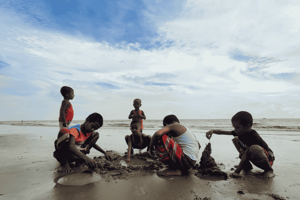 anak kecil sedang bermain pasir pantai saat liburan keluarga