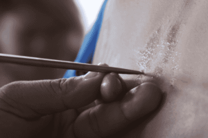 Proses ritual tato Sak Yant Thailand oleh biksu dengan batang logam tradisional